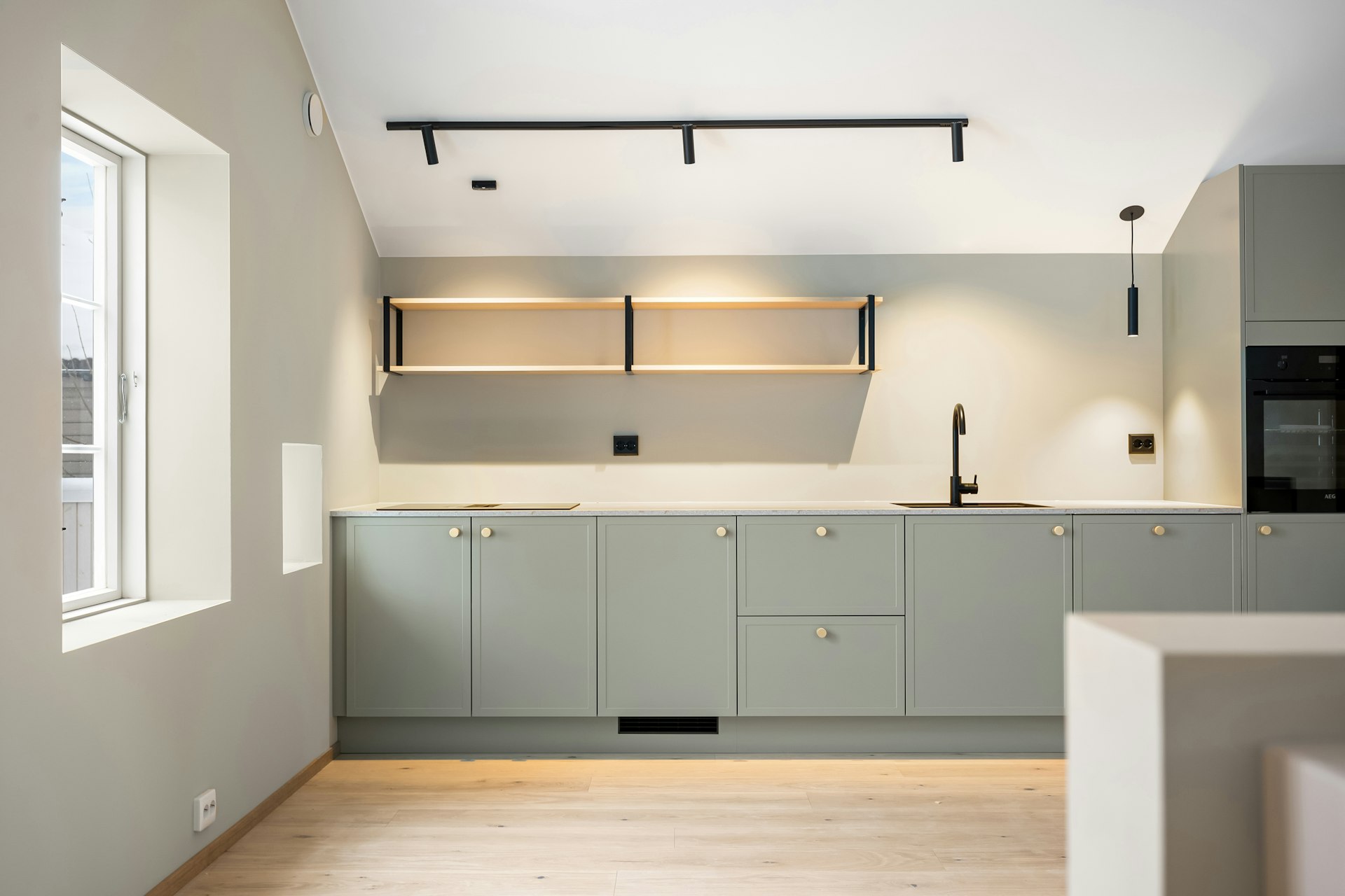 A kitchen with a window, a sink, cabinets and a microwave